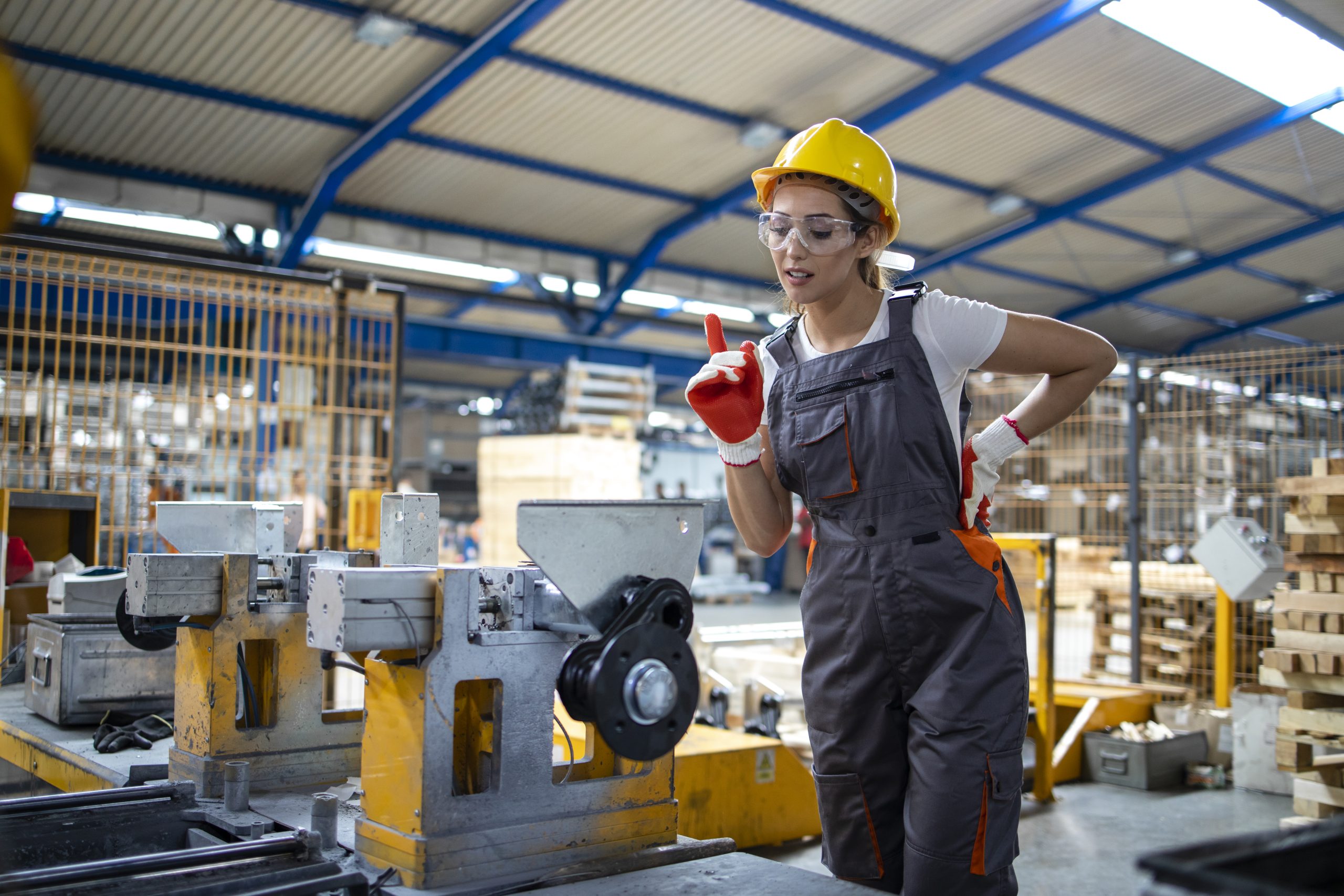 Female factory worker operating industrial machine in production line.